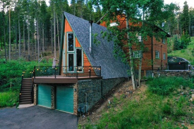 The Evergreen Aerie A-frame exterior at dusk with string lights and teal garage doors