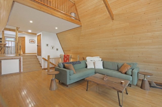 Lower-level living area with sectional sofa and staircase to the loft